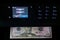 Black multifunction printer with touch screen display makes copy of 50 dollar bill in the dark. Printing money.