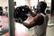 Black muscular man in a white T-shirt fastens damn for a barbell