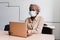 Black muslim business woman in medical mask with laptop. Working on line at home. Cryptocurrency investments in bitcoin