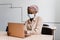 Black muslim business woman in medical mask with laptop. Working on line at home. Cryptocurrency investments in bitcoin