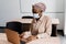 Black muslim business woman in medical mask with laptop. Working on line at home. Cryptocurrency investments in bitcoin