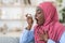 Black muslim woman in hijab using inhaler at home, suffering breathing problem