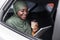 Black muslim woman riding car on backseat with digital tablet and coffee