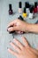 Black nail polish being applied to hand with tools for manicure on background. Beautiful process. Close up.