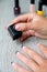 Black nail polish being applied to hand with tools for manicure on background. Beautiful process. Close up.