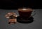 Black, natural, fragrant coffee in the transparent cup on a black background, with milk chocolate.