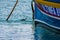 Black-necked grebe, Podiceps nigricollis, swimming next to a colourful Maltese fishing boat.