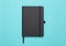 Black notebook isolated on blue background. Flat lay or Top view angle.
