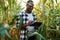Black notepad is in hands. Young African American man is standing in the cornfield at daytime