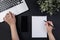 Black office desk with laptop and white mockup notepad