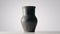 Black old jug. Handmade jar from clay rotating on white table isolated on light gray background in studio. Earthenware