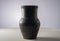 Black old jug. Handmade jar from clay standing on white table isolated on gray background in studio. Earthenware for