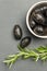 Black olives. Bella di cerignola Italian olives. Colored olives and a sprig of rosemary lie on a black stone countertop