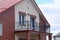 Black open iron balcony on the facade of a brown brick house with a window and door