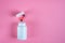 Black and orange pills, tablets and white bottle on pink background