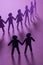 Black paper figure of male couple in front of a crowd of paper people holding hands on purple surface. Social movement