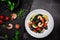 Black Pasta - Squid Ink, with Prawns, Seafood,Lemon and Tomatoes in White Bowl on  Dark Background. Top view