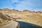 Black paved road in Death Valley winding through desert