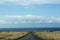 A black paved road leading to the Pacific Ocean through grasslands in Hawaii