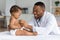 Black Pediatrician Doctor Doing Check Up To Cute Newborn Baby In Diaper