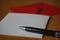 Black pen writing announcement letter with the envelope on the wooden desk