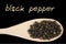 Black pepper on wooden spoon isolated on black background. Latin name Piper nigrum