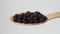 Black peppercorns in a wooden spoon. Falling black pepper seeds