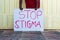 Black person holding a sign with text Stop Stigma``