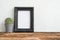 Black photo frame on old wooden table with cactus over white con