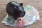 Black piggy bank on pile of Euro banknotes on wooden table, financial savings money account concept, future growth of interest co