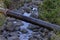 Black pipe crossing the rocky narrow stream