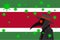 Black plague doctor surrounded by viruses with copy space with SURINAME flag