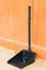 Black plastic dustpan with orange bricks wall