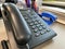 Black plastic office landline corded telephone with a handset and buttons for solving business problems and making calls for