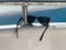 Black plastic sunglasses hang on an iron railing on a yacht, a cruise liner against the blue sea and mountains