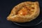 Black plate with Adjarian Khachapuri â€“ Georgian cheese bread on dark textured background. Baked open pie with cheese and egg