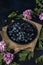 Black plate with blueberry, blackberry and acacia flowers on the burlap napkin and dark background