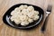 Black plate with boiled dumpling and fork on table