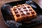 Black plate with homemade belgian waffles with Sifting sugar powder.