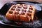 Black plate with homemade belgian waffles with Sifting sugar powder.