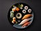 a black plate with sushi on it and a candle on the side of the plate and a candle on the side of the