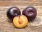 Black plums isolated on wooden background