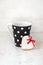 Black polka dotted coffee cup with a heart shaped homemade cookie over white wood background.