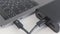 Black portable external power bank, for emergency device recharge. Action. Close up of an open laptop is charged with a