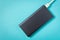 Black power Bank with adapter for charging mobile devices on a blue background