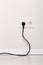 Black power cord cable plugged into european wall outlet on whit