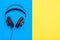 Black professional earphones with wire on blue and yellow background