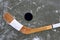 Black puck and hockey stick lying on a ice rink.
