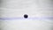 Black puck rotates on ice of ice hockey stadium