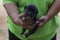 A black puppy looking at camera and was carried by the owner.